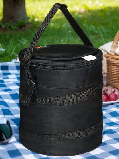 Black cooler bag with shoulder strap shown outdoors on a picnic table